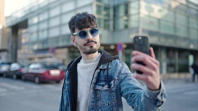 Young hispanic man smiling confident making selfie with smartphone at street