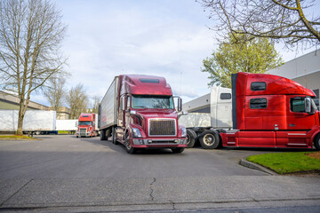 Warehouse parking lot filled with big rig semi trucks with refrigerator semi trailers loaded during a busy working day