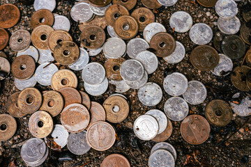 Japanese coins lie as an offering on the damp wall of a shrine. Silver and copper coins.