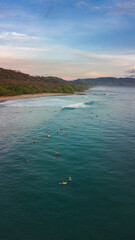 Aerial photography in Costa Rica, surfer enjoying waves and nature during sunset colors