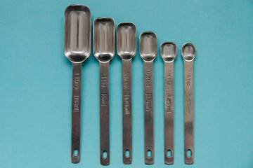 group of stainless steel tablespoons and teaspoons on a blue background
