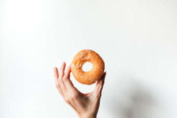 hand holding sweet delicious glazed donut on white background.