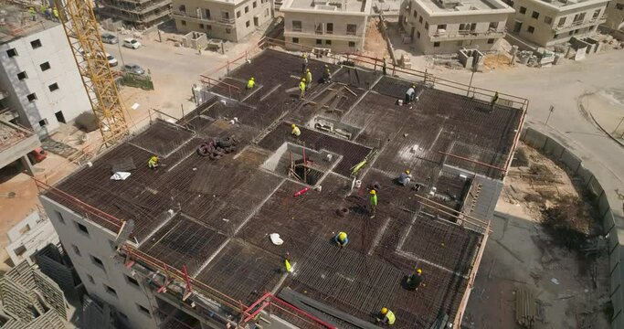 Workers working on the roof of a building construction. Area under construction next to a desert area. aerial drone shot