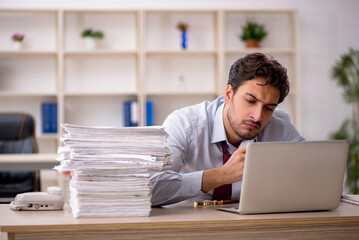 Young male employee and too much work in the office