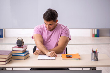 Fototapeta na wymiar Young male student preparing for exams in time management concep