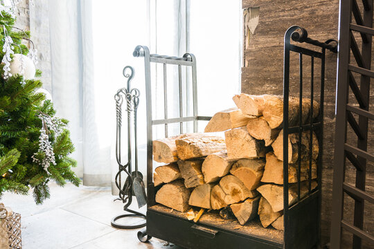 Stack of firewood logs by a fireplace and Christmas tree in hotel lobby