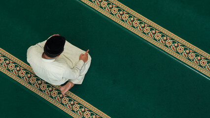 Top view of muslim man praying on the carpet at the mosque