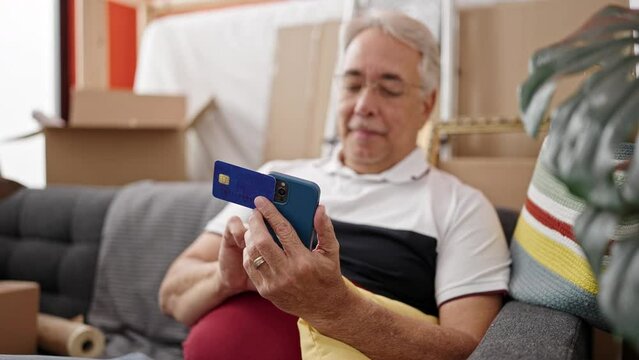 Middle age man with grey hair smiling confident using smartphone doing online shopping at new home