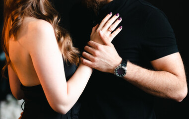 Hands of embracing man and woman in black clothes