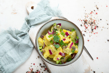Delicious new potato salad with red onion, capers, greens in a bowl.