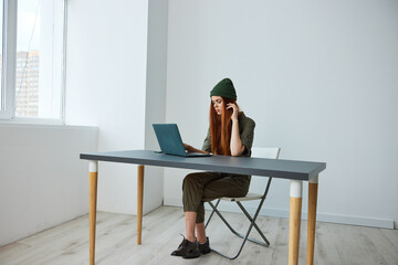 woman working in the office sitting at a table with a laptop in a hat