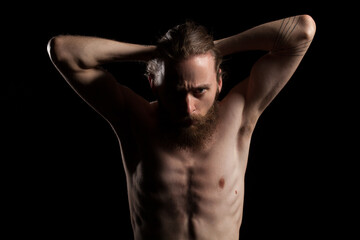 Fototapeta na wymiar Cool looking bearded man in deep shadows and black background in studio photo