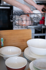 Women's hands sort clean dishes from the dishwasher