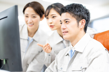 パソコンを見る作業着を着た日本人男女