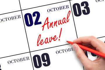 Hand writing the text ANNUAL LEAVE and drawing the sun on the calendar date October 2