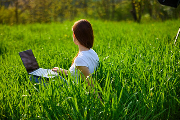 businesswoman working on a laptop while on vacation in nature in a field