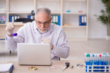 Old male chemist working at the lab