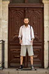 Cool hipster in white shirt posing in front of a door. Style and diversity