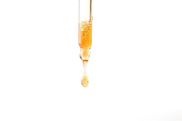 Dropper pipette with orange liquid drop on the whte isolated background. Oil, serum, acid cosmetic sample Close up.Copy space - obrazy, fototapety, plakaty