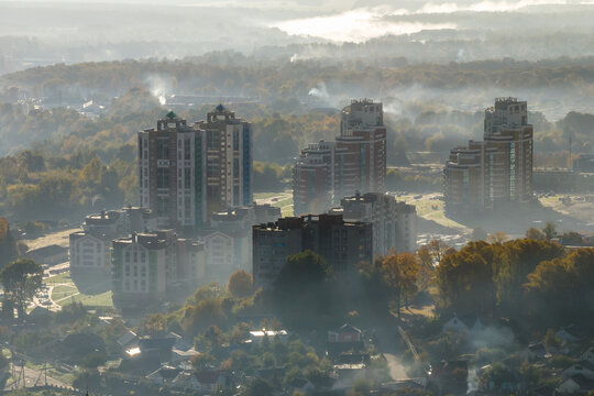 aerial view of green city with skysrapers and residential buildings in earning fog and mist