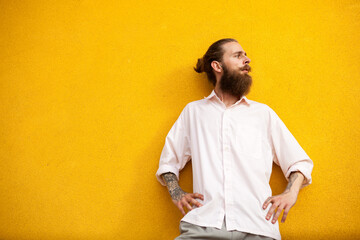 Bearded hipster on yellow vintage wall looking cool. Outside fashion shooting