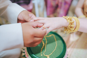The groom is wearing a wedding ring to the bride. Wedding in thailand.