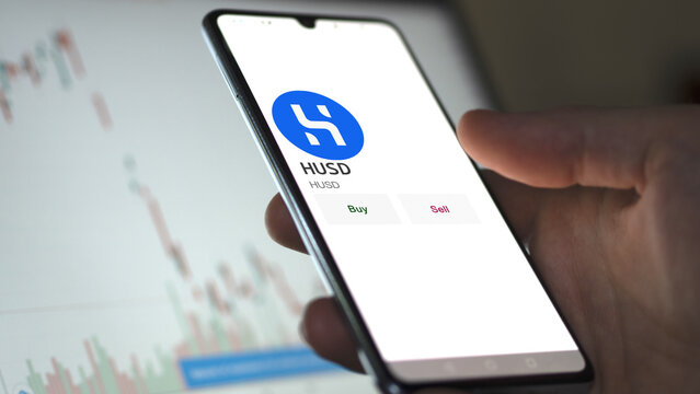 March 11 2023 London UK. An investor's analyzing the HUSD  coin on screen. A phone shows the ETF's prices to invest in HUSD