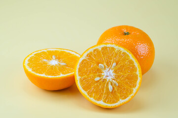 Fresh cut oranges and oranges isolated on soft yellow background