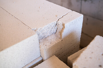 Cracked freshly delivered aerated concrete brick close-up. White porous brick with a chipped piece, fragile building materials