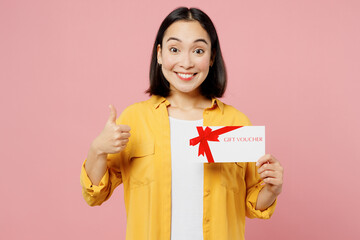 Young happy woman of Asian ethnicity wear yellow shirt white t-shirt hold gift certificate coupon...