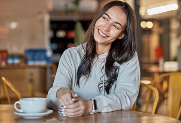 Fototapeta na wymiar Thinking, happy and a woman waiting in a coffee shop, sitting at a table to relax over the weekend. Idea, cafe and smile with an attractive young female sitting in a restaurant feeling thoughtful