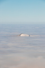 Fototapeta premium View of the top of Mount Skalka in the Beskydy Mountains under the cover of thick white fog in the morning hours. Snowy hills with clouds. Being above the clouds