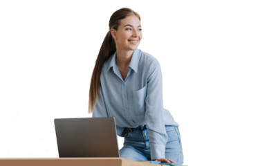 Gorgeous blonde young woman in blue shirt and blue jeans standing at desk with laptop looks aside toothy smiles against transparent background. Pretty female model with ponytail remote working home.