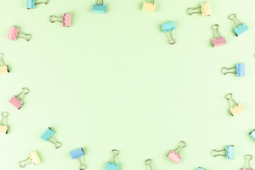 Colorful binder clips on green background, flat lay. Space for text