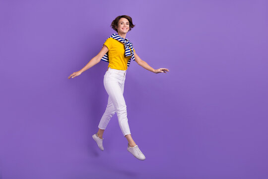 Full length photo of cheerful glad adorable lady moving empty space enjoy walk free time good mood isolated on purple color background