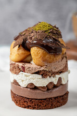 Layered profiteroles cake. Whipped cream, chocolate, and pistachio cake. Close up.