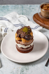 Layered profiteroles cake. Whipped cream, chocolate, and pistachio cake.