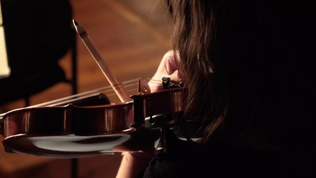 Girl tunning the violin over the shoulder