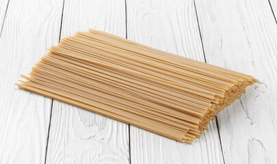 Uncooked spaghetti pasta on white wooden background