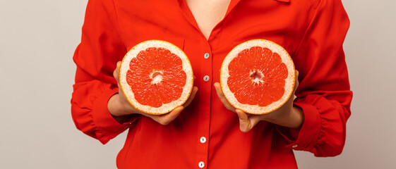 Banner size shot of a woman holding grapefruit halves in front of her breasts.