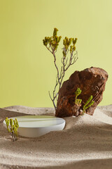 A round podium in white color putted on the sand with green trees and a big block of stone. Blank space to display product