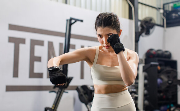 Asian young muscular fit strong body sporty athletic sexy female fitness in sportswear sport bra leggings gloves standing guarding footwork boxing training exercising punching workout in Crossfit gym