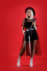 Violinist woman in the stage costume on the red background.