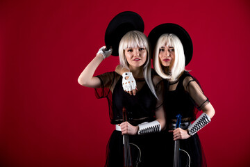 Violinist women duet in the stage costumes on the red background.
