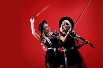Violinist women duet in the stage costumes on the red background.
