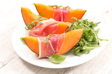Sliced melon with ham and basil leaves