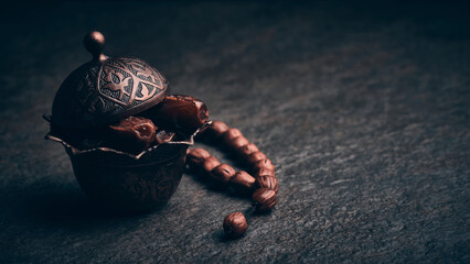 Ramadan Kareem. Dates in traditional middle-eastern brass bowl and juniper wood rosary beads at...