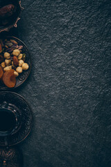Iftar. Fasting during Islam Holy Month. Ramadan Kareem. Dates, dried apricots, nut mix and tea in traditional arabian style brass holder at stone surface flat lay with copy space