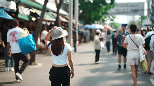 woman traveler visiting in Bangkok, Tourist with hat sightseeing in Chatuchak Weekend Market, landmark and popular attractions in Bangkok, Thailand. Travel in Southeast Asia concept