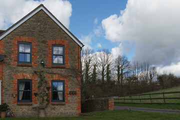 Home Exterior in United Kingdom. Old farmhouse exterior image. Located in England in the Somerset countryside. Contemporary doors and windows in traditional farm house building.